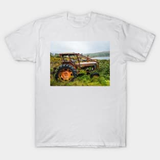 Old rusty tractor overgrown with weeds near a lake T-Shirt